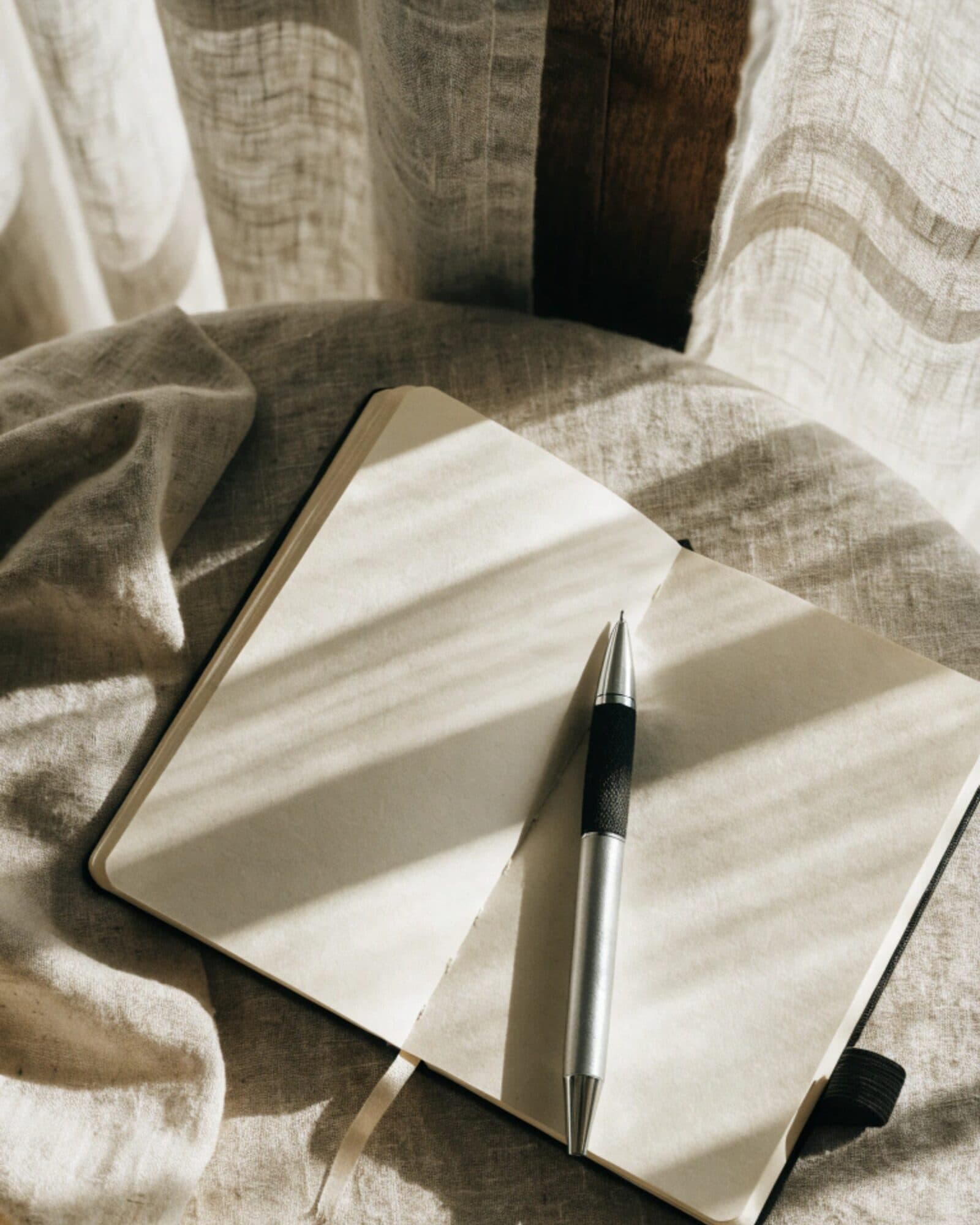 An open notebook and pen on linen